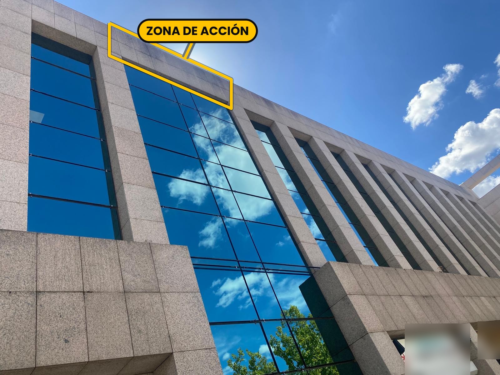 Coronación de granito de la fachada de un edificio comercial de Las Rozas de Madrid antes de la limpieza con drones, con la zona de acción delimitada en amarillo