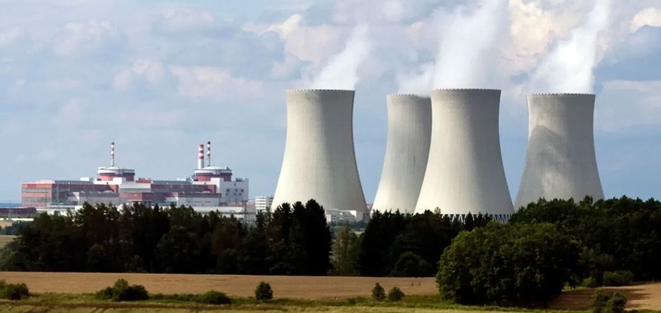 Técnicos con chaleco reflectante operando un dron frente a torres de refrigeración