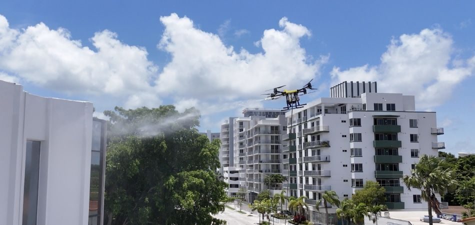 Dron limpiando la fachada de un bloque residencial mientras el equipo opera desde la calle