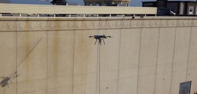 Dron limpiando un paramento de hormigón de gran superficie en un edificio industrial